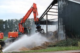 Hooi in schuur vliegt in brand, graafmachines halen hooi uit schuur