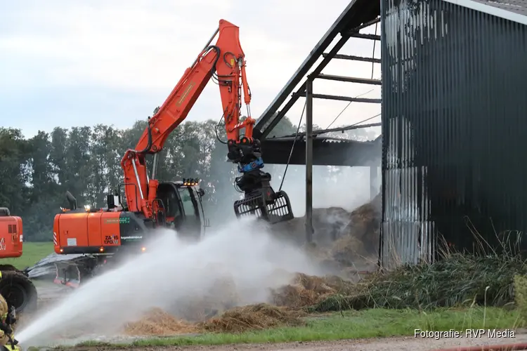 Hooi in schuur vliegt in brand, graafmachines halen hooi uit schuur