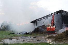 Hooi in schuur vliegt in brand, graafmachines halen hooi uit schuur