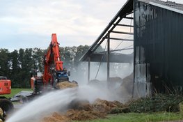 Hooi in schuur vliegt in brand, graafmachines halen hooi uit schuur
